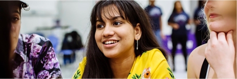 Student wearing yellow top and chatting.
